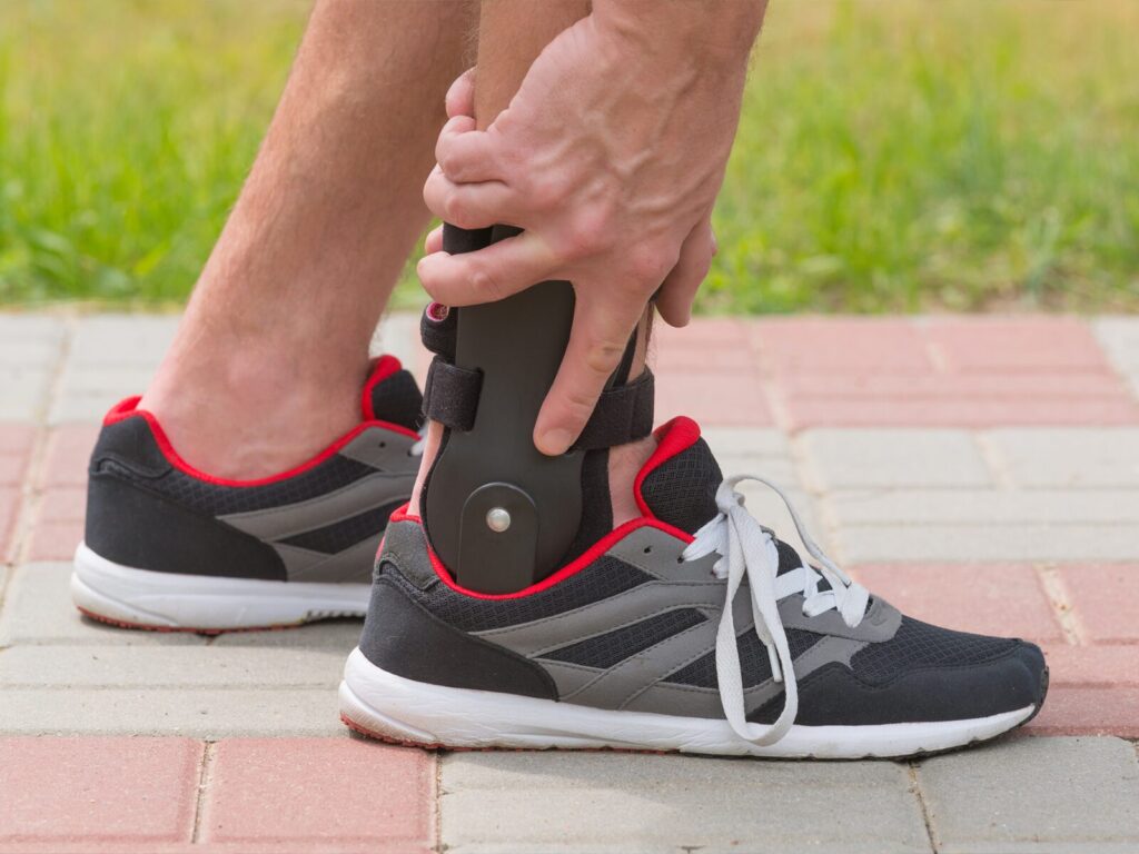 Man in running shoes wears an orthopedic brace on his angle
