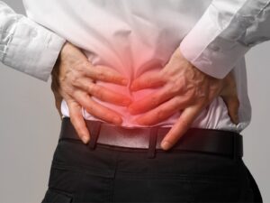 Man in suit clutches his lower back in pain