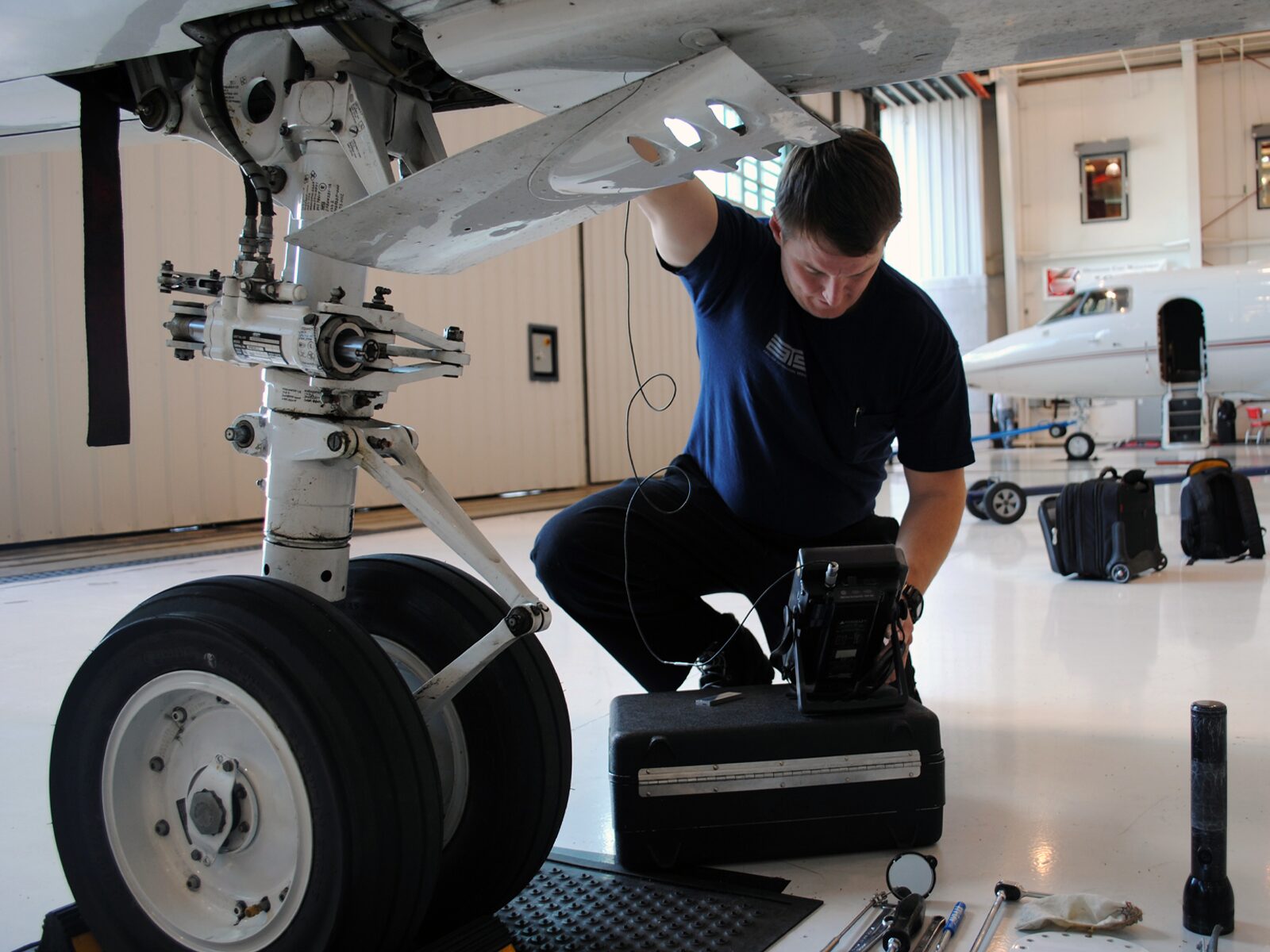 NDT technician performs an eddy current inspection of a plane's landing gear