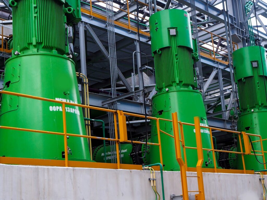 Three large vertical pumps at a chemical or oil facility