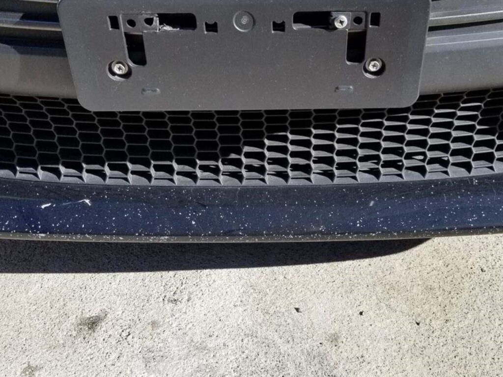 Focus on the fender of a car. The paint is chipped from gravel and loose rock impact.