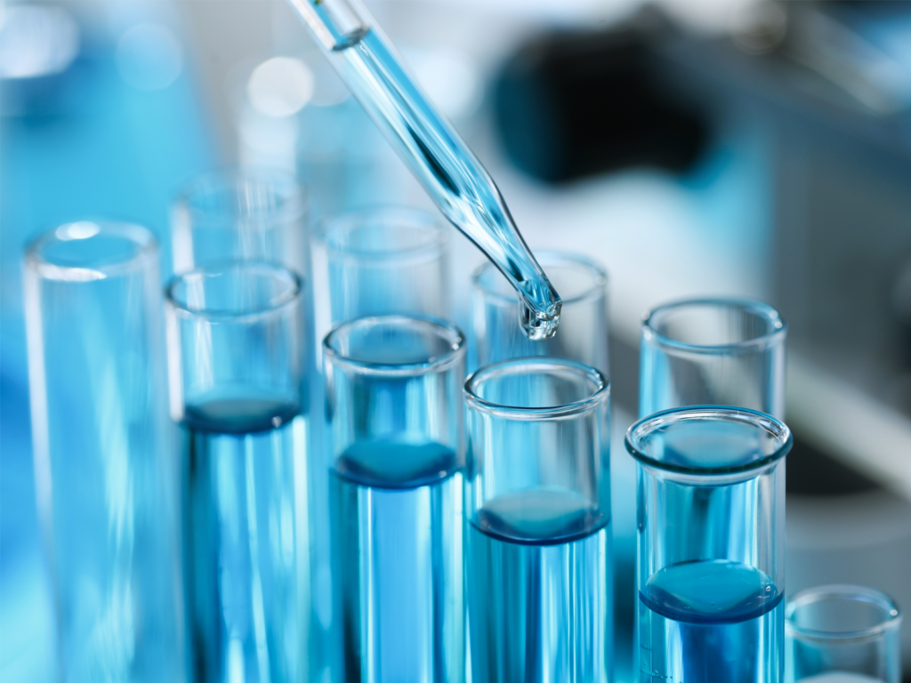 An eyedropper fills a series of beakers with a blue chemical solution.