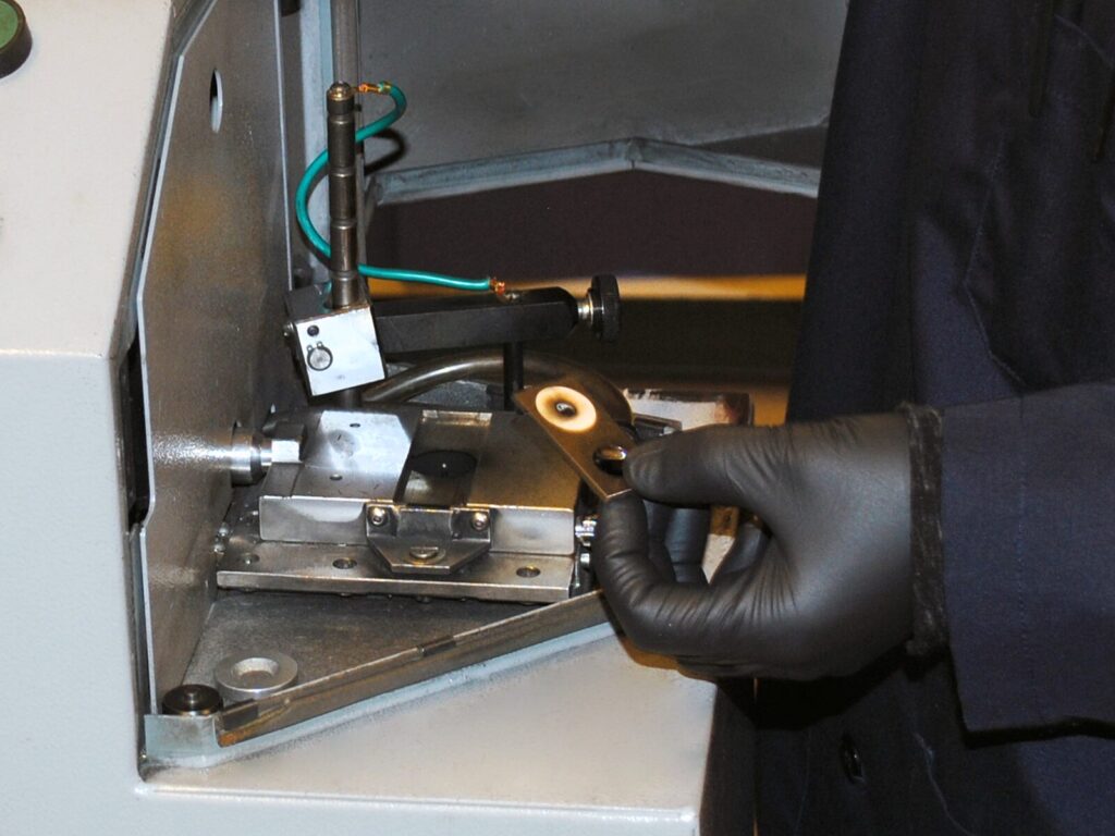 Chemist holds a charred disk after optical emission spectroscopy.