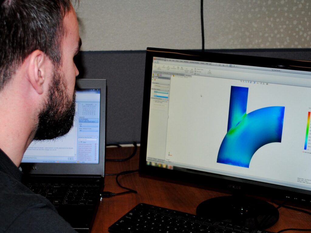 Engineer looks at finite element analysis of a pipeline on a computer screen