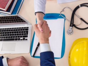 Doctors shakes hands with an engineer over a table