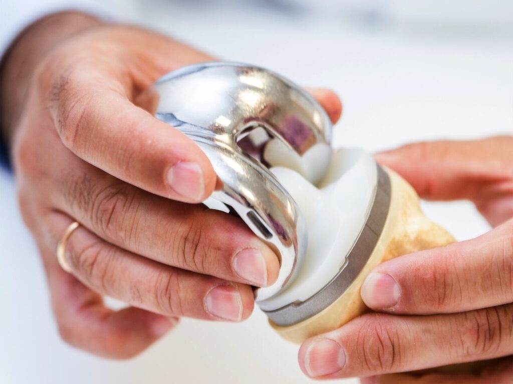 Close up on two hands holding a total knee replacement device