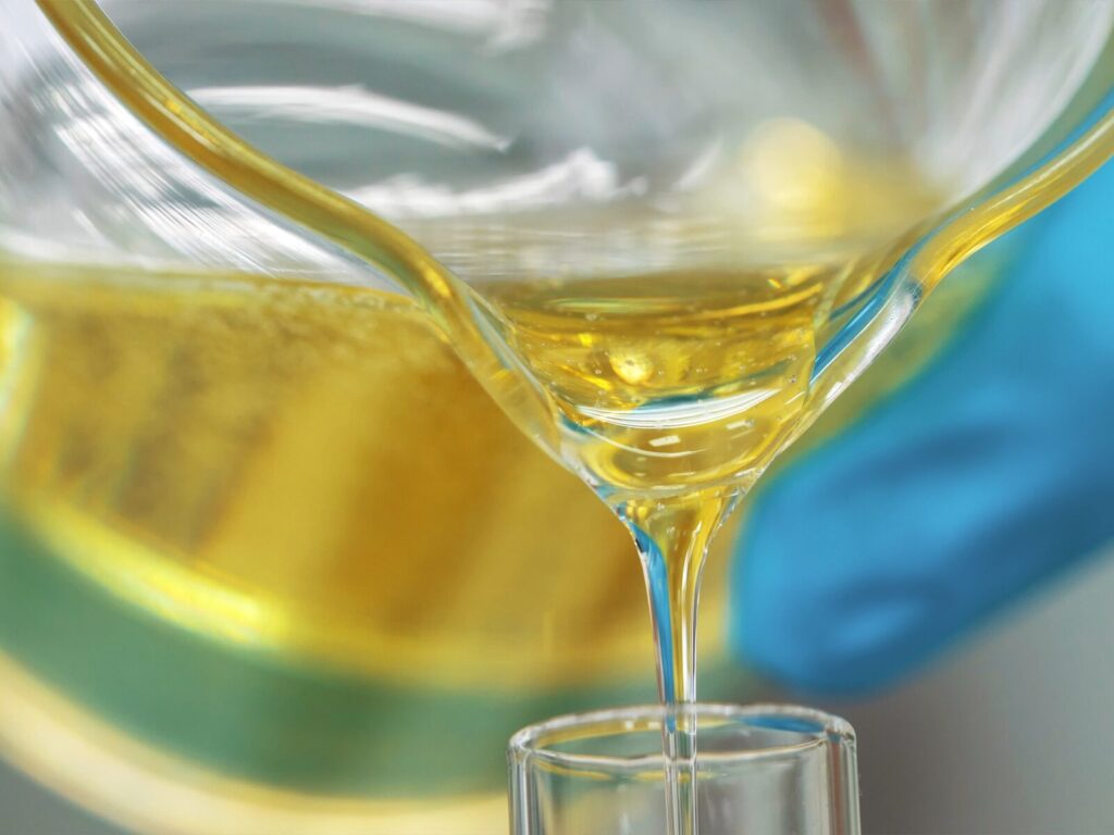 A chemist pours lubricating oil into a test tube for analysis