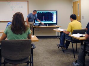 Man demonstrates how to use an Eddy Current Tester to students.