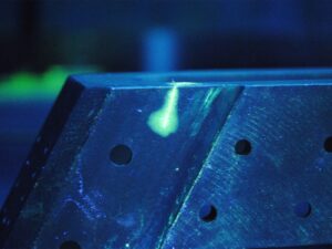 Liquid penetrant solution in a cracked component under fluorescent light.