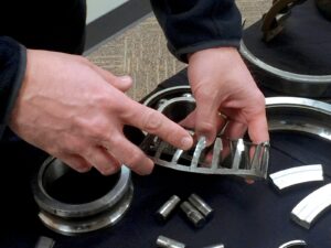 Technician holds a failed gear. He points to one of the teeth.
